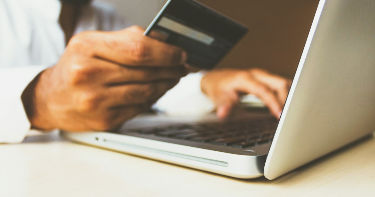 Customer holding a debit card while shopping online on a laptop