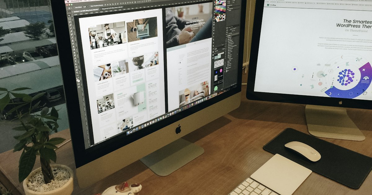 Web designer working on a business website layout on two monitors